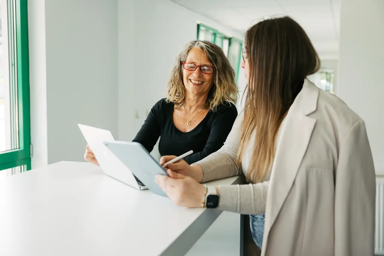 Unsere Ausbilderin Andrea mit einer Kollegin in einer Meetingsituation im VEDA-Gebäude.