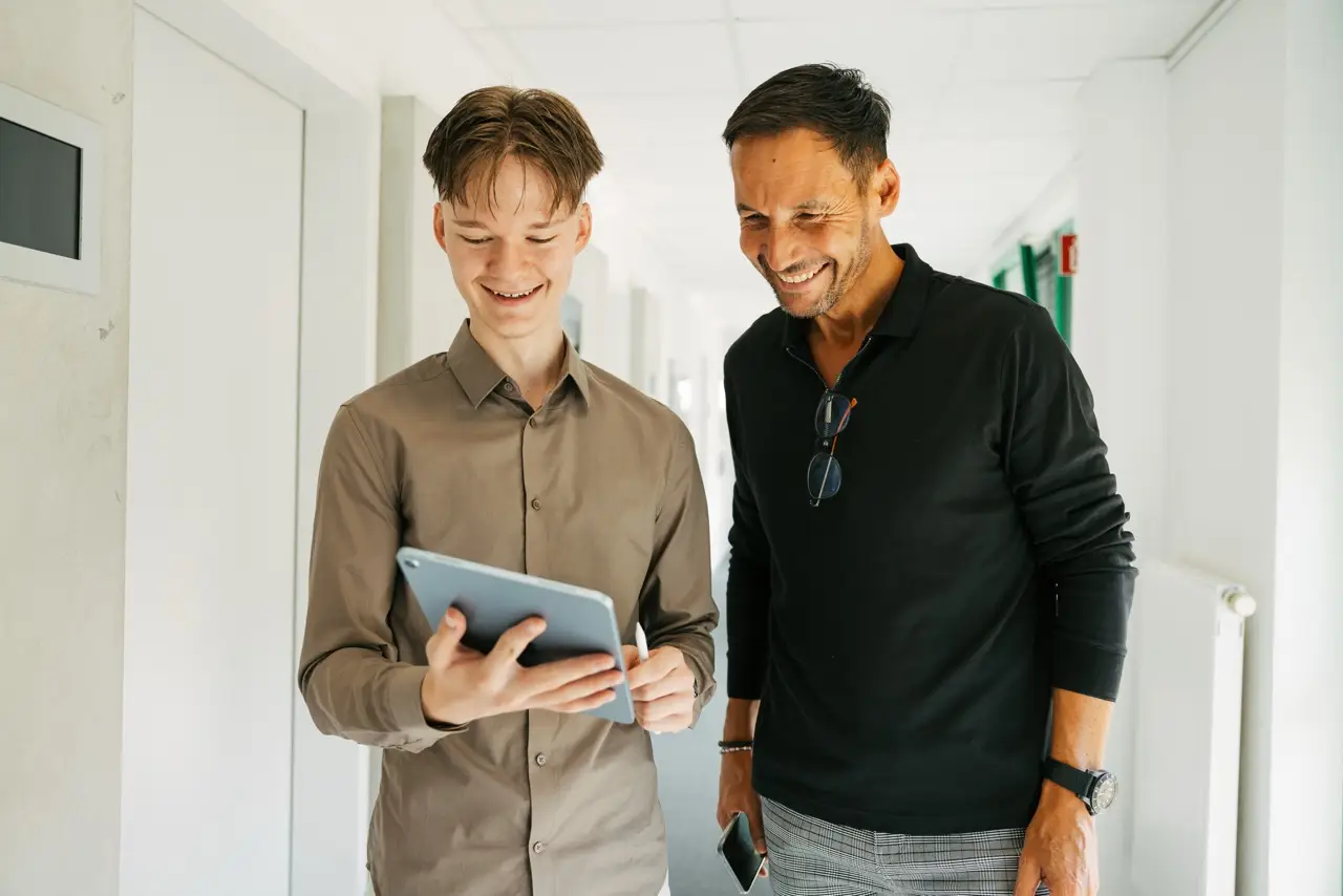 Zwei VEDA Kollegen tauschen sich aus und schauen auf ein iPad.