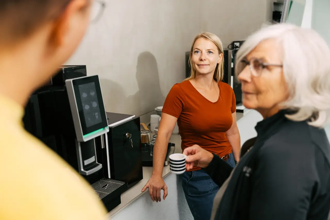 VEDA-Mitarbeiter:innen stehen gemeinsam an der Kaffeemaschine.