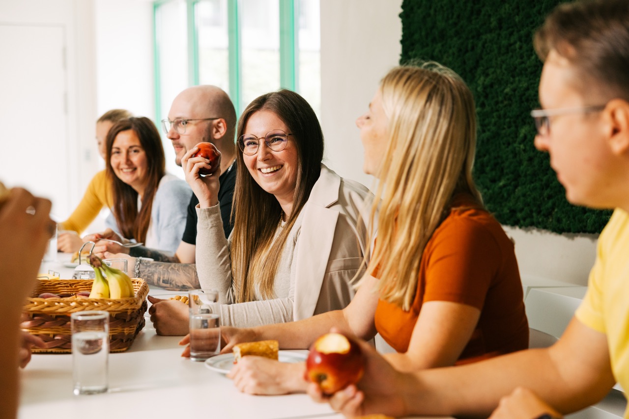 VEDA-Mitarbeiter:innen sitzen gemeinsam an einem Tisch in der Cafeteria.