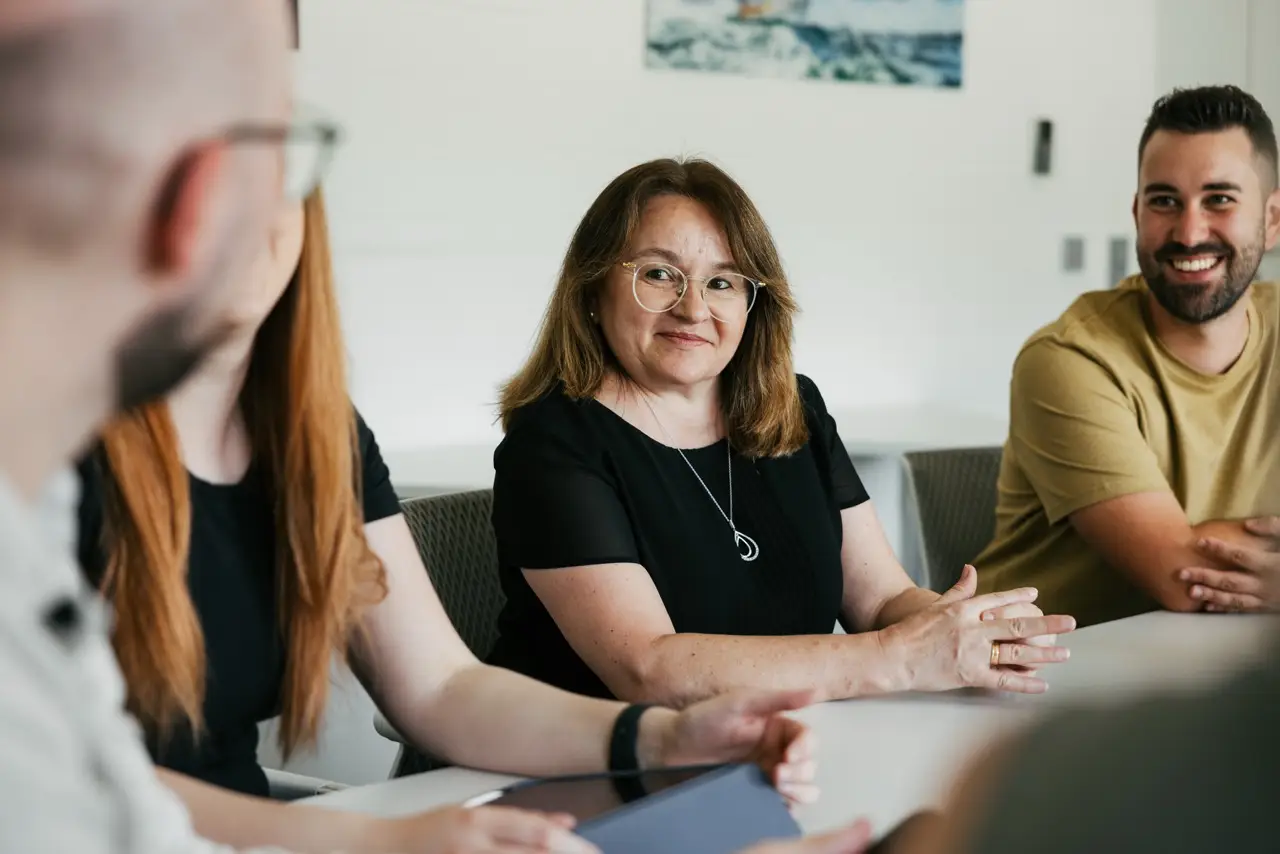 VEDA Kolleg:innen sitzen in einem Konferenzraum zusammen und hören aktiv zu.